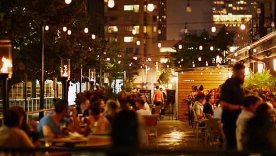 Guests enjoy evening al fresco dining on an outdoor patio under twinkling lights.